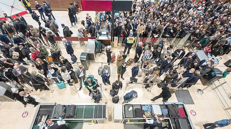 Passagiere stehen an einer Sicherheitskontrolle am Flughafen BER Schlange. Foto: Christophe Gateau/dpa