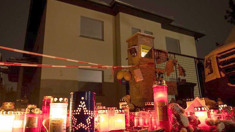 Kerzen brennen auf dem Gehweg vor dem Einfamilienhaus Königs Wusterhausen, wo Polizisten eine Familie tot aufgefunden hatten. Foto: Christophe Gateau/dpa