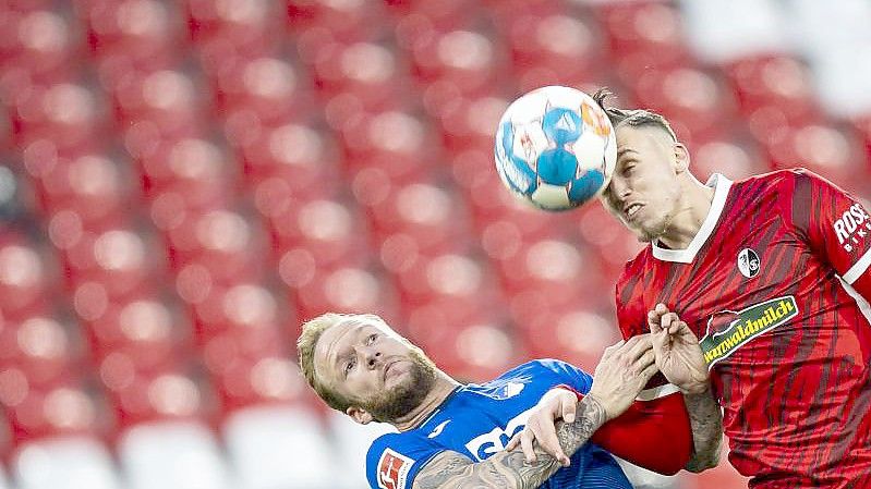 Der Freiburger Ermedin Demirovic (r) im Kopfballduell mit Kevin Vogt. Foto: Tom Weller/dpa