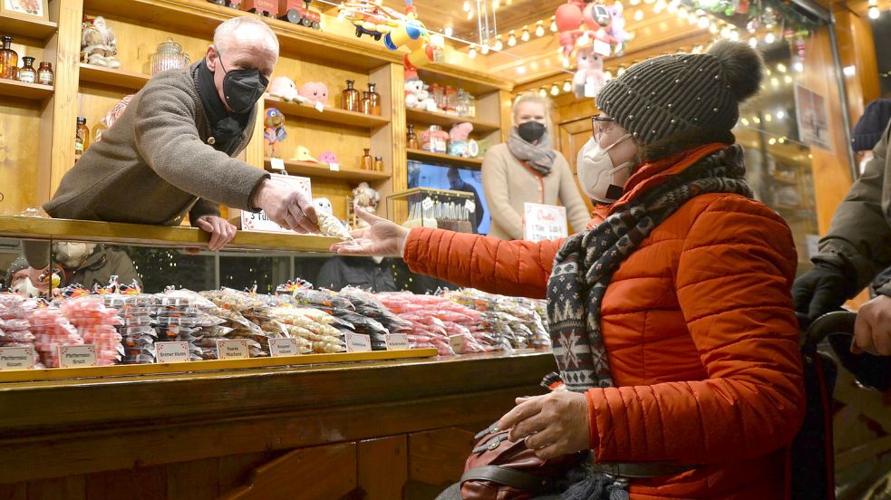 Georg Horz verkauft an eine Kundin Bonbons. Auf dem Auricher Weihnachtsmarkt war mehr los als in den vergangenen Tagen. Foto: Franziska Otto