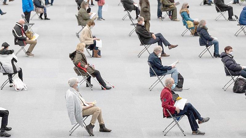 Menschen sitzen am ersten Tag des Impfmarathons in der August-Schärttner-Halle in Hanau und warten darauf, dass sie geimpft werden. Foto: Sebastian Gollnow/dpa