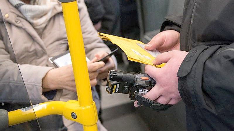 Ein Prüfdienst-Mitarbeiter der Verkehrsbetriebe Hamburg-Holstein (VHH) kontrolliert in einem Bus den 3-G-Nachweis einer Passagierin. Foto: Daniel Bockwoldt/dpa