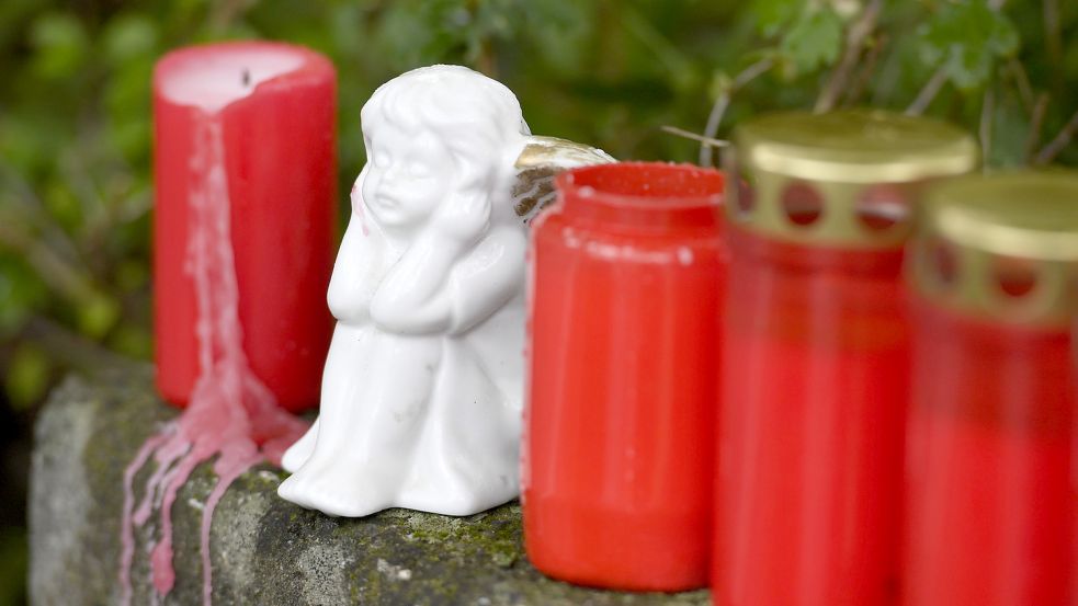 Eine Porzellanfigur steht zwischen Kerzen. Foto: DPA