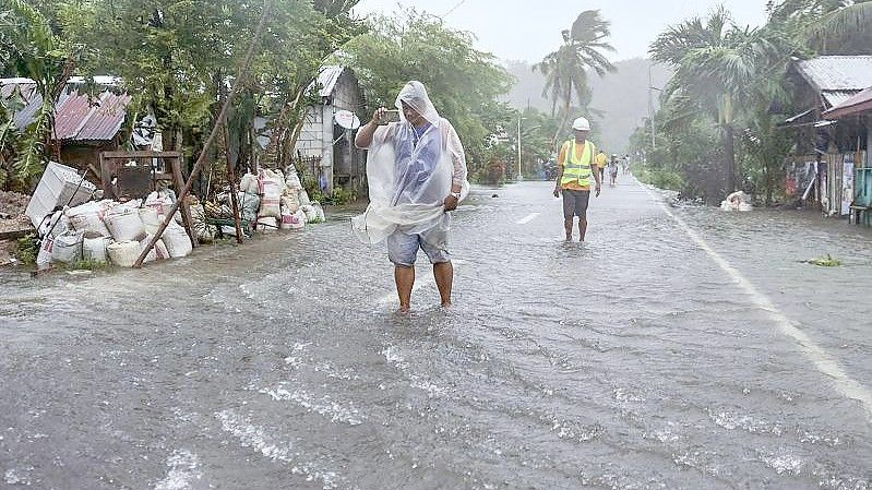 Einheimische waten durch überflutete Straße in Guiuan. Foto: Alren Beronio/AP/dpa