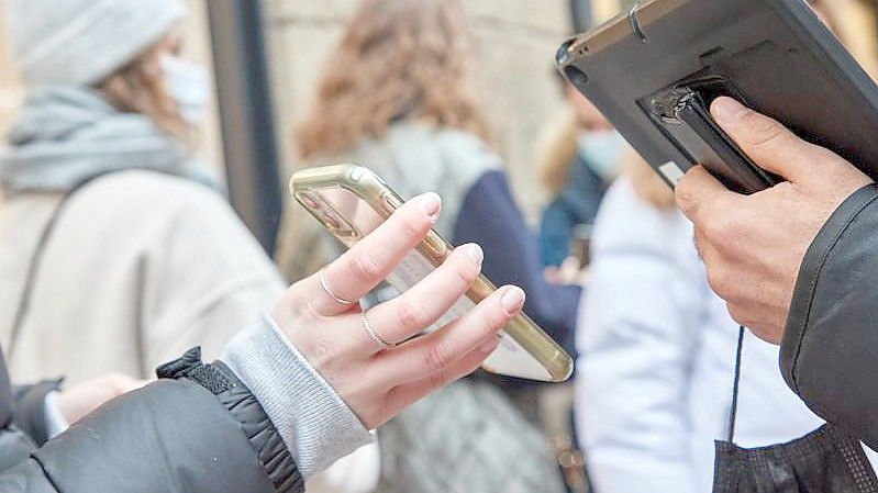 Ein Security-Mitarbeiter kontrolliert vor einem Geschäft in Hamburg den Impfstatus einer Kundin. Foto: Georg Wendt/dpa