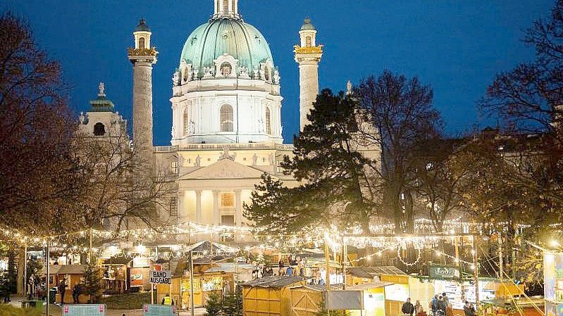 Menschen besuchen den Christkindlmarkt am Karlsplatz in Wien. Foto: Georg Hochmuth/APA/dpa