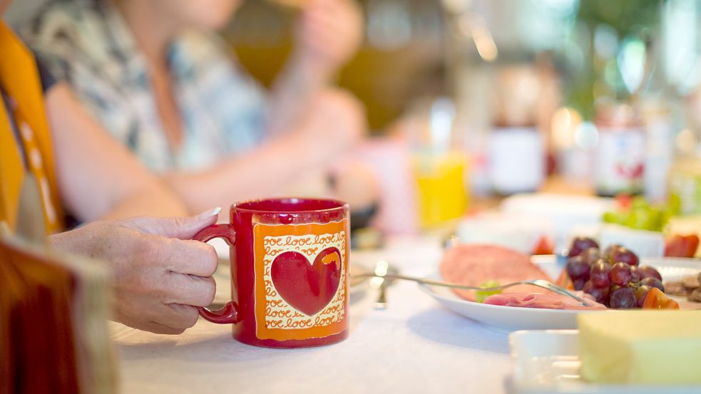 Eine rote Tasse steht auf einem gedeckten Tisch. Foto: DPA