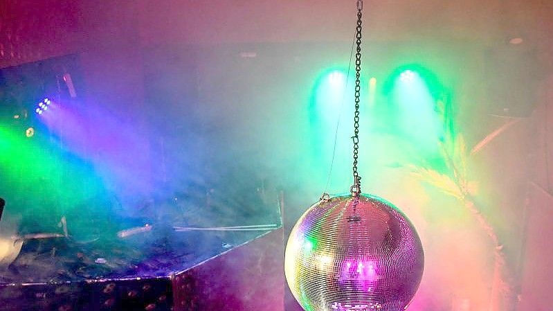 Eine Diskokugel dreht sich in einem Club und reflektiert das einfallende Licht der Scheinwerfer und Lampen. Foto: Britta Pedersen/dpa-Zentralbild/dpa
