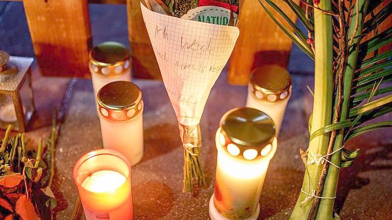 Kerzen, Blumen und ein Blumenstrauß stehen vor dem Eingang zu dem Haus, in dem am zweiten Weihnachtstag drei Menschen einer vierköpfigen Familie tot gefunden wurden. Foto: Axel Heimken/dpa