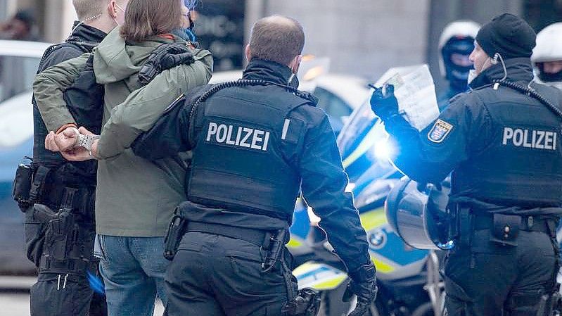 Polizisten in Frankfurt am Main nehmen eine Teilnehmerin einer Corona-Demonstration fest. Foto: Boris Roessler/dpa