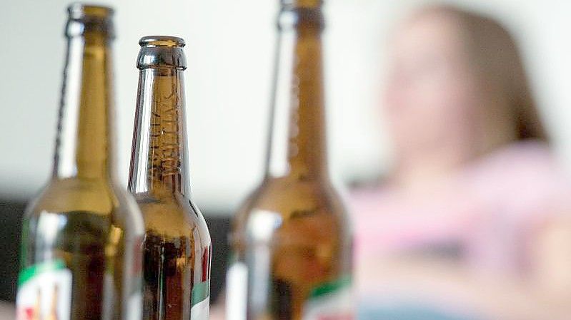 „Der Suchtkranke kreist nur um sich selbst und hat die Kinder nicht im Blick“: Eine Frau hinter leeren Bierflaschen. Foto: Alexander Heinl/dpa