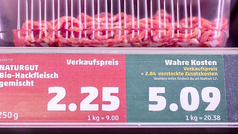 Ein Preisschild in einem Supermarkt weist neben dem Verkaufspreis auch den „wahren Preis“ aus. Foto: Rolf Vennenbernd/dpa