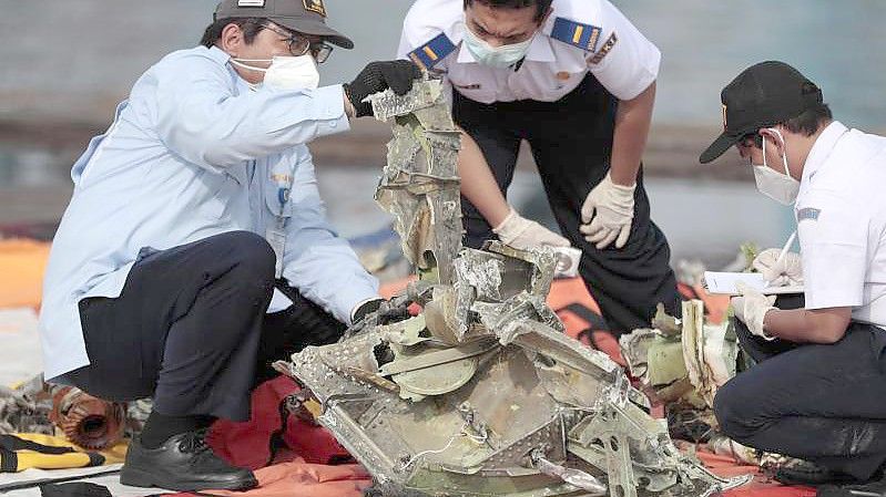 Ermittler inspizieren ein Wrackteil des Sriwijaya Air Flugzeugs SJ-182. Die Überreste wurden aus der Javasee geborgen, wo das Passagierflugzeug am 09.01.2021 abgestürzt war. (Archivbild). Foto: Dita Alangkara/AP/dpa