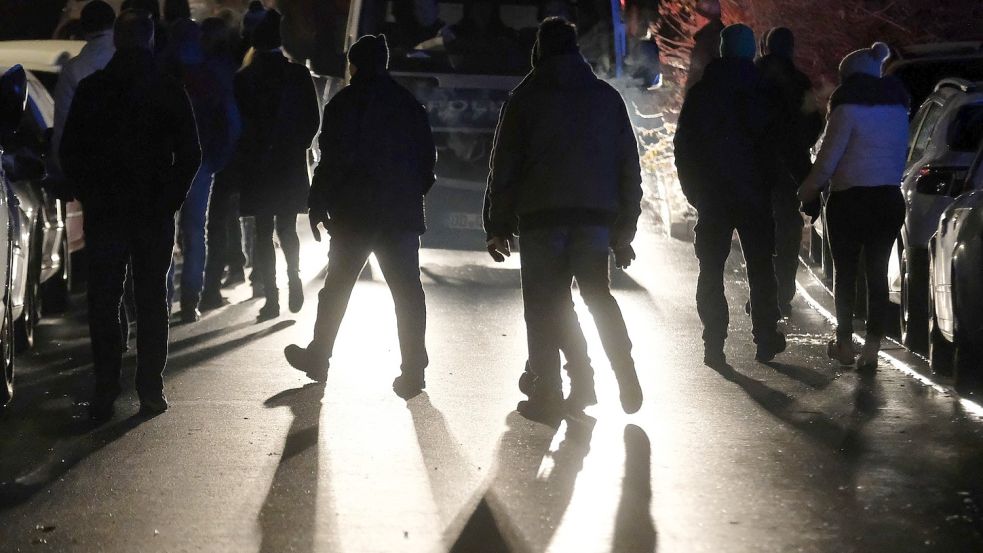 Kritiker der Coronamaßnahmen gehen eine Straße entlang. Foto: DPA