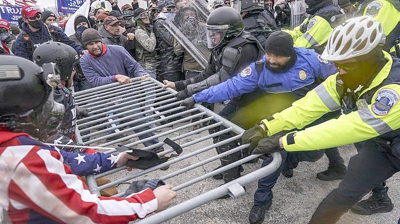 Trump-Anhänger versuchen, vor dem Kapitol durch eine Polizeiabsperrung zu brechen. Foto: John Minchillo/AP/dpa