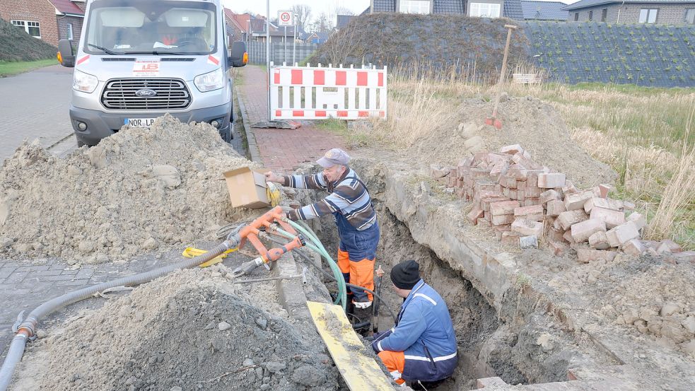 Mitarbeiter des Bauunternehmens Ludwig Bold aus Norden reparieren das defekte Kabel, das die Siedlung Am Geestrand in Hage mit Strom versorgt. Foto: Kim Hüsing