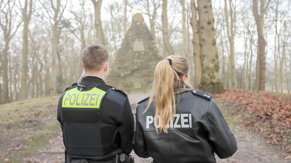 Zwei Polizisten stehen vor dem Auricher Kulturdenkmal Upstalsboom. Foto: Romuald Banik