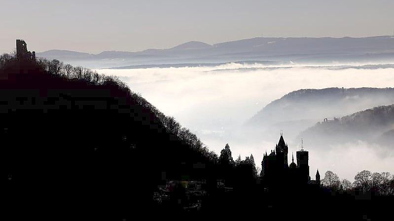 Hinter Schloss Drachenburg (r) und der Burg Drachenfels ziehen Nebelschwaden durch das Rheintal. Foto: Oliver Berg/dpa