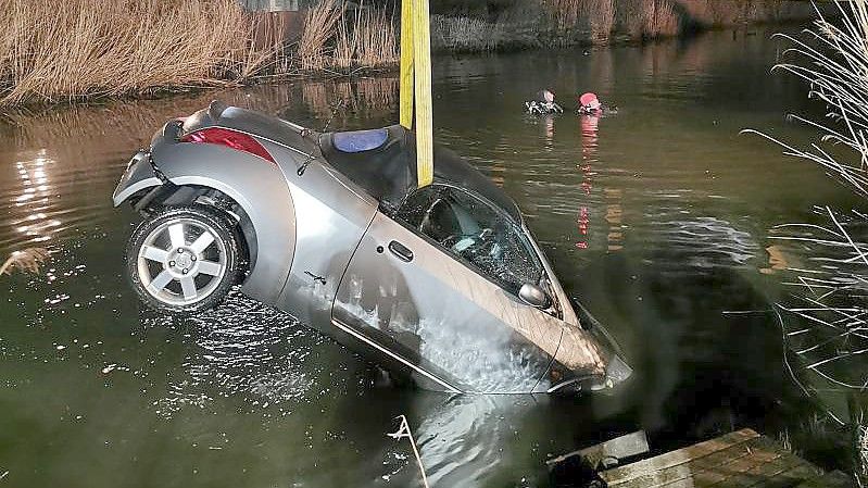 Taucher im Einsatz - eins der versunkenen Autos wird mit einem Kran geborgen. Foto: Feuerwehr Emden/dpa