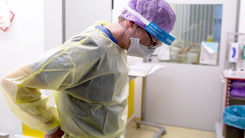 Ein Arzt des Krankenhauses Düren zieht seine Schutzkleidung an, um auf der Intensivstation des Krankenhauses Düren einen Covidpatienten zu untersuchen. (Archivbild). Foto: Thomas Banneyer/dpa