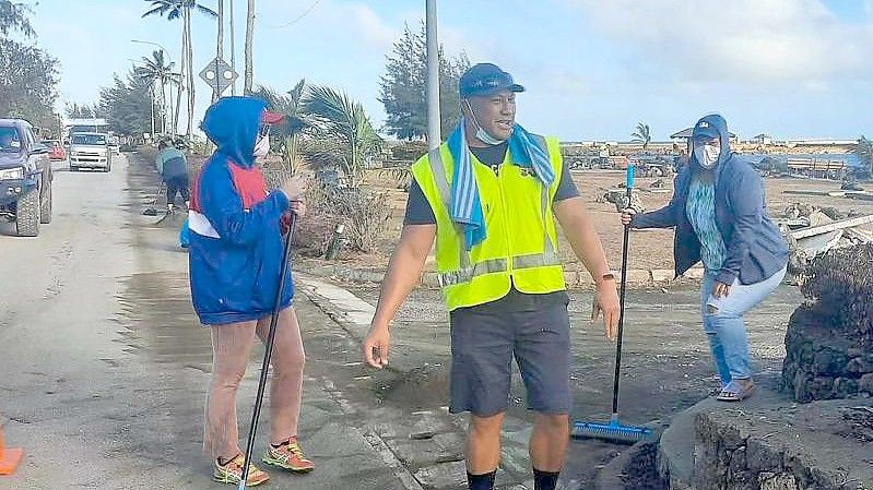 Anwohner fegen Asche von einer Straße nach dem Ausbruch eines unterseeischen Vulkans vor Tonga. Foto: Marian Kupu/XinHua/dpa