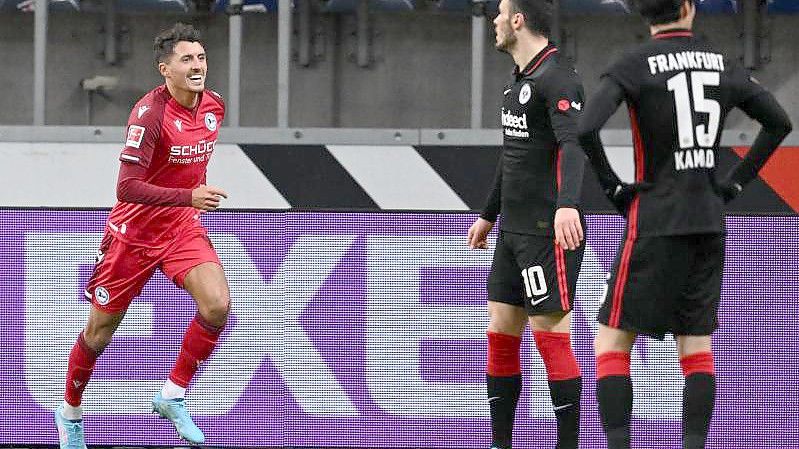 Bielefelds Alessandro Schöpf (l) feiert sein Tor zur 2:0-Führung neben den Frankfurtern Filip Kostic (M) und Daichi Kamada. Foto: Arne Dedert/dpa