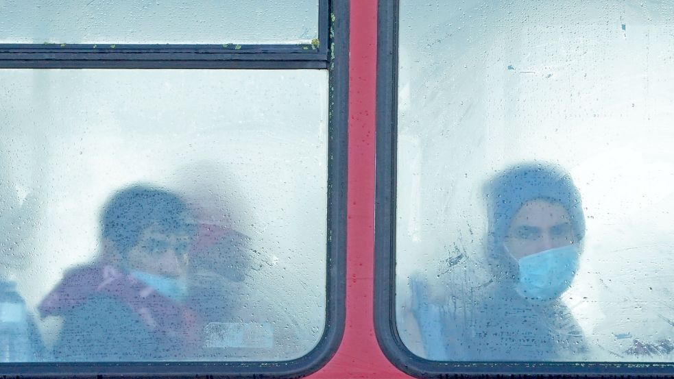 Eine Gruppe von Menschen, bei denen es sich vermutlich um Migranten handelt, sitzt in einem Bus. Foto: DPA