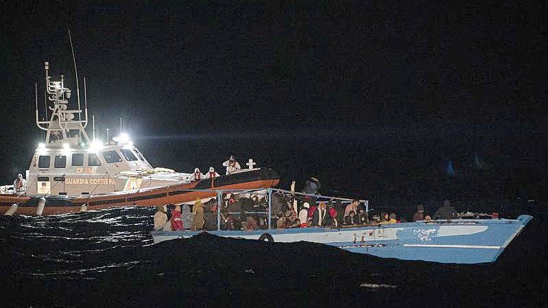 Ein Schiff der Küstenwache fährt zu dem völlig überfüllten Holzboot vor Lampedusa. Foto: Pau De La Calle/AP/dpa