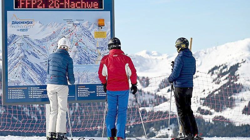 Skifahrer vor einer Informationstafel mit der Aufforderung nach FFP2-Masken und 2G-Nachweis im Skigebiet Altenmarkt-Zauchensee. Foto: Barbara Gindl/APA/dpa