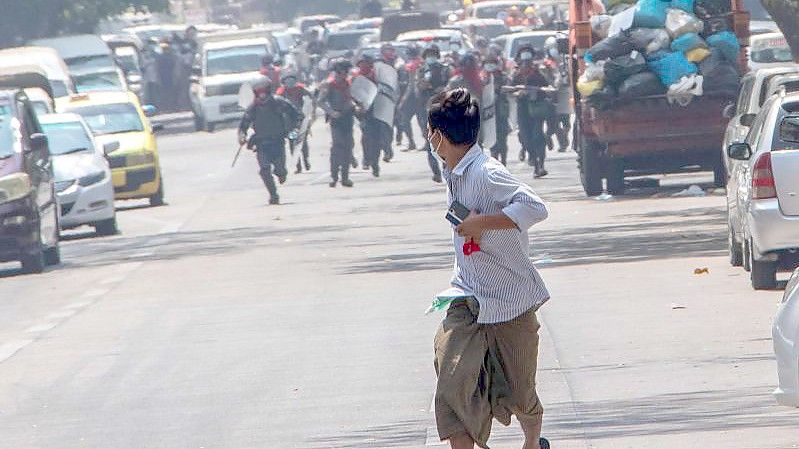 Bereitschaftspolizisten rennen einem Demonstranten in Rangun hinterher. (Archivbild). Foto: Santosh Krl/SOPA Images via ZUMA Wire/dpa