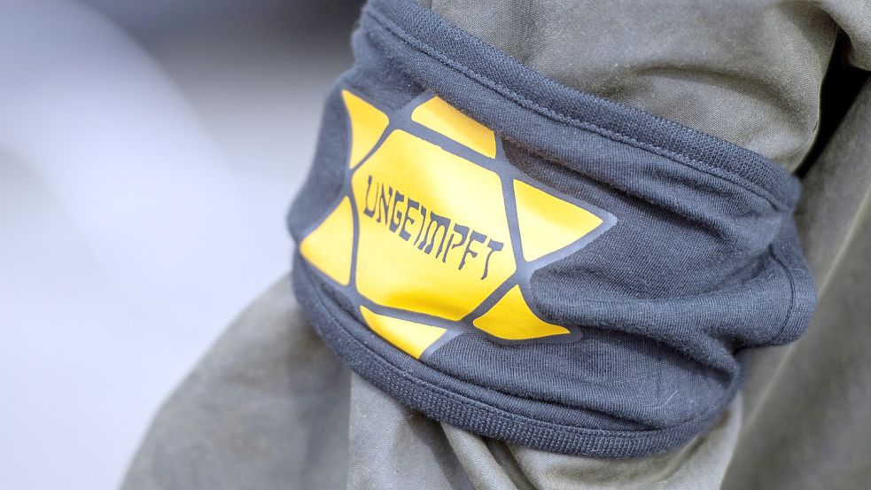 Bei einer Demonstration gegen die Einschränkungen durch die Pandemie-Maßnahmen der Bundesregierung am Brandenburger Tor trägt ein Teilnehmer eine Armbinde mit einem gelben Stern, der an einen Judenstern erinnern soll, mit der Aufschrift «Ungeimpft». Foto: dpa/Christophe Gateau