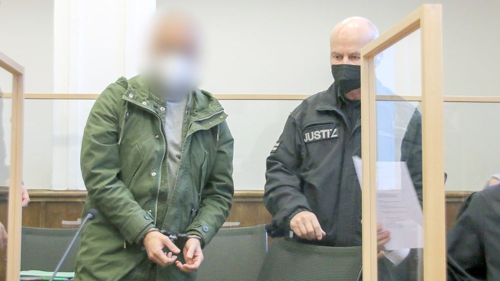 Ein Angeklagter wird von einem Justizbediensteten am ersten Verhandlungstag des Schleuser-Prozesses vor dem Landgericht Aurich an seinen Platz geführt. Foto: DPA