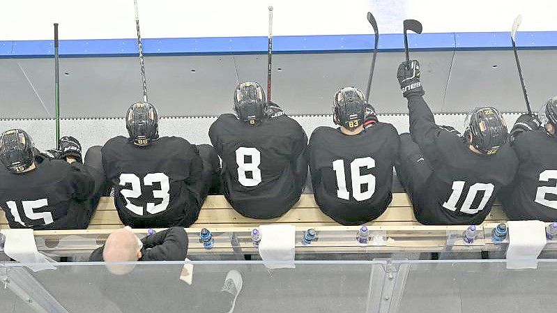 Spieler der deutschen Eishockey-Nationalmannschaft sitzen bei einer Trainingseinheit auf der Bank. Foto: Peter Kneffel/dpa