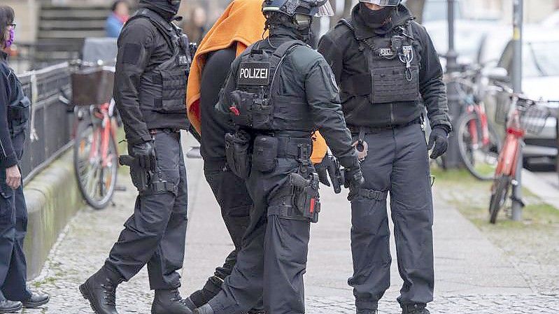 Polizisten bringen den Angeklagten unter einer Decke aus dem Gerichtsgebäude in Berlin. Foto: Christophe Gateau/dpa