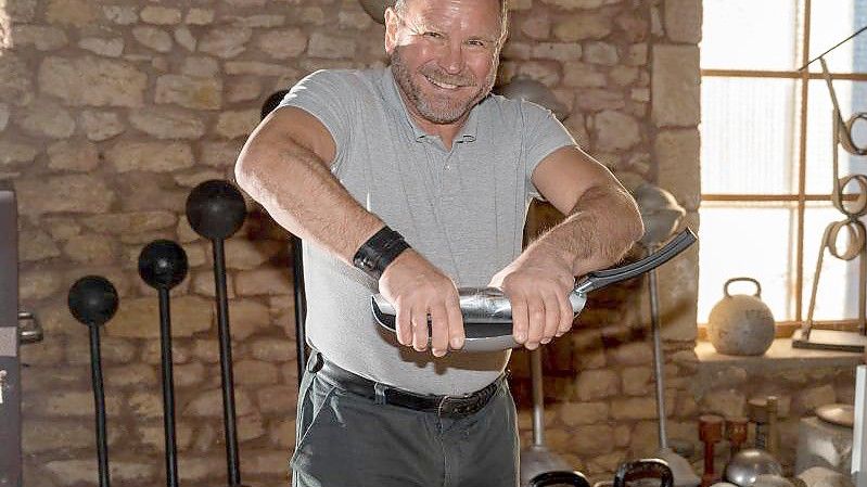 Georges Christen rollt mit bloßen Händen in seiner Trainingsscheune eine handelsübliche Bratpfanne zusammen. Foto: Harald Tittel/dpa