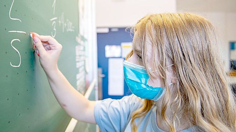 Eine Schülerin trägt im Unterricht eine Maske. Foto: Guido Kirchner/dpa/Archivbild