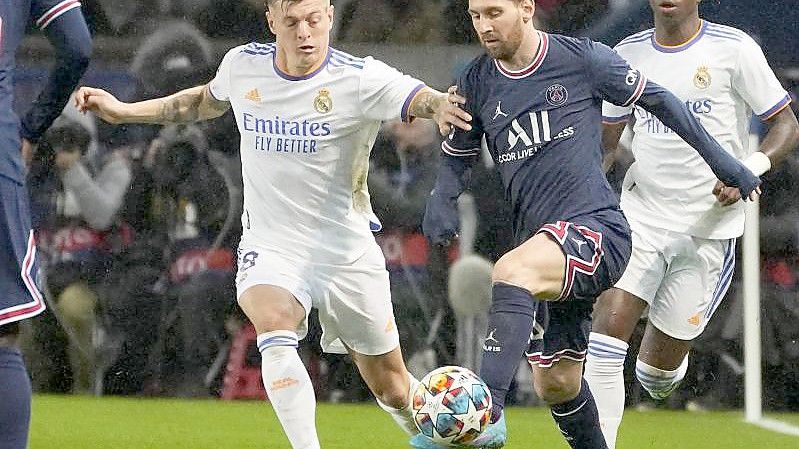 Lionel Messi (2.v.r) von PSG wird von Real Madrids Toni Kroos bedrängt. Foto: Michel Euler/AP/dpa