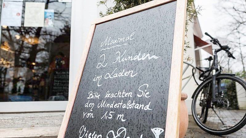 Eine Tafel vor einem Münchener Geschäft weist auf die Maximalanzahl von 2 Personen im Laden hin. Foto: Matthias Balk/dpa
