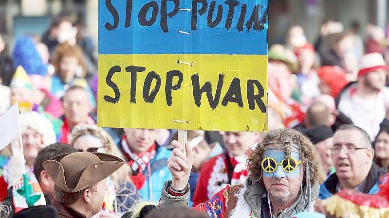 Protestplakat gegen den Krieg beim Kölner Straßenkarneval. Foto: Oliver Berg/dpa