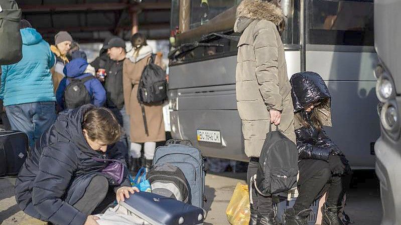 Ukrainische Bürger bereiten sich an einem Bahnhof im Westen der Ukraine vor, in einen Bus nach Polen einzusteigen. Foto: Bernat Armangue/AP/dpa
