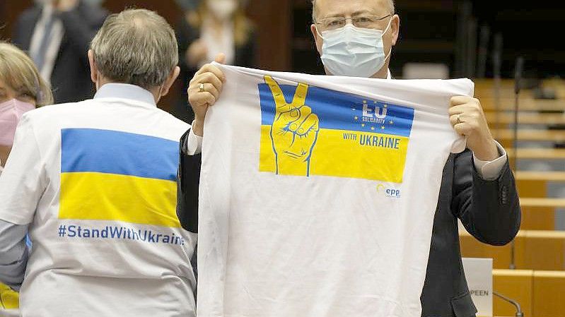 Ein Mitglied des Europäischen Parlaments hält ein T-Shirt in den Farben Blau und Gelb zur Unterstützung der Ukraine. Foto: Virginia Mayo/AP/dpa