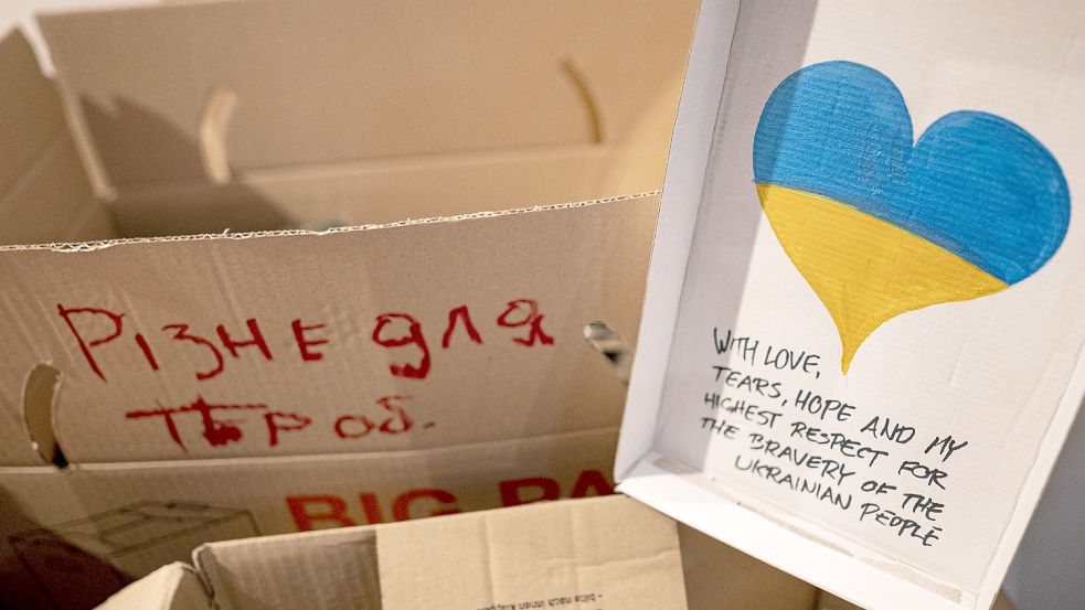 Neben Kartons mit Spenden ist ein Schild mit der ukrainischen Flagge in Herzform mit den Worten „With love, tears, hope and my highest respect for the bravery of the ukrainian people“. Foto: DPA