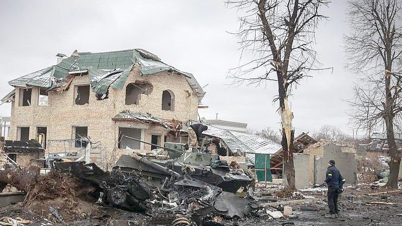 Ein Mann betrachtet die ausgebrannten Überreste russischer Militärfahrzeuge in Butscha. Foto: Serhii Nuzhnenko/AP/dpa