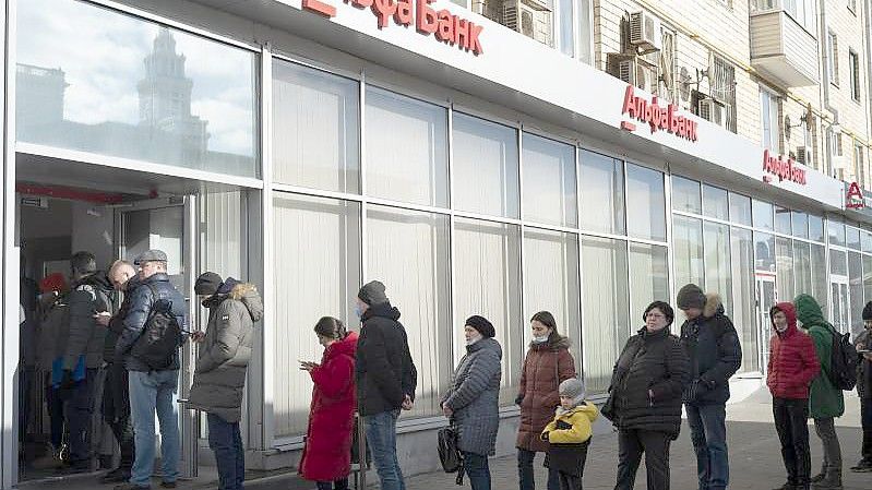 Menschen in Moskau stehen vor einem Geldautomaten der Alfa Bank Schlange. Foto: Victor Berzkin/AP/dpa
