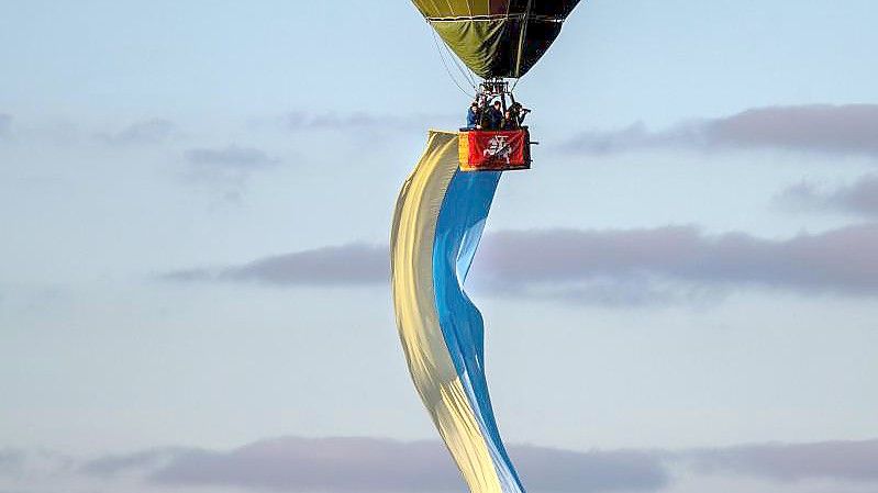 Über Litauens Hauptstadt Vilnius schwebt während der Proteste für den Frieden in der Ukraine ein Heißluftballon in den Farben der ukrainischen Flagge. Foto: Mindaugas Kulbis/AP/dpa