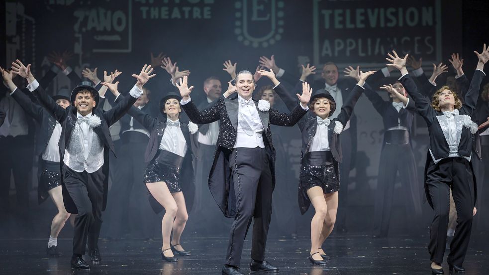 Großes Musical: Wenn Dance Company und Chor Don Lockwood (Alexander von Hugo, Mitte) umgeben, entstehen große, bühnentaugliche Tableaus bei der Premiere von „Singin’ In The Rain’ im Theater Osnabrück. Foto: Stephan Glagla