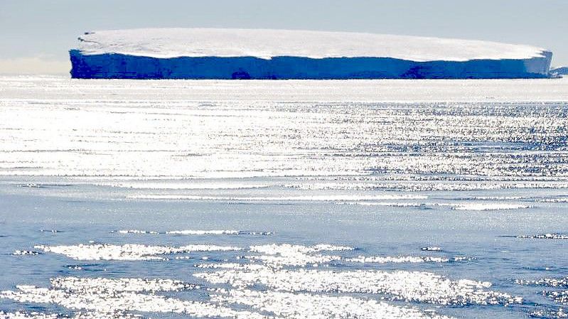 Eisschollen treiben in der Antarktis vor einem Eisberg. Das Eis dehnt sich immer weniger aus. Foto: picture alliance / Hans-Christian Wöste/dpa