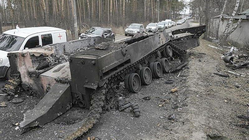 Autos fahren an einem zerstörten russischen Panzer in der Nähe von Irpin am Stadtrand von Kiew vorbei. Foto: Vadim Ghirda/AP/dpa
