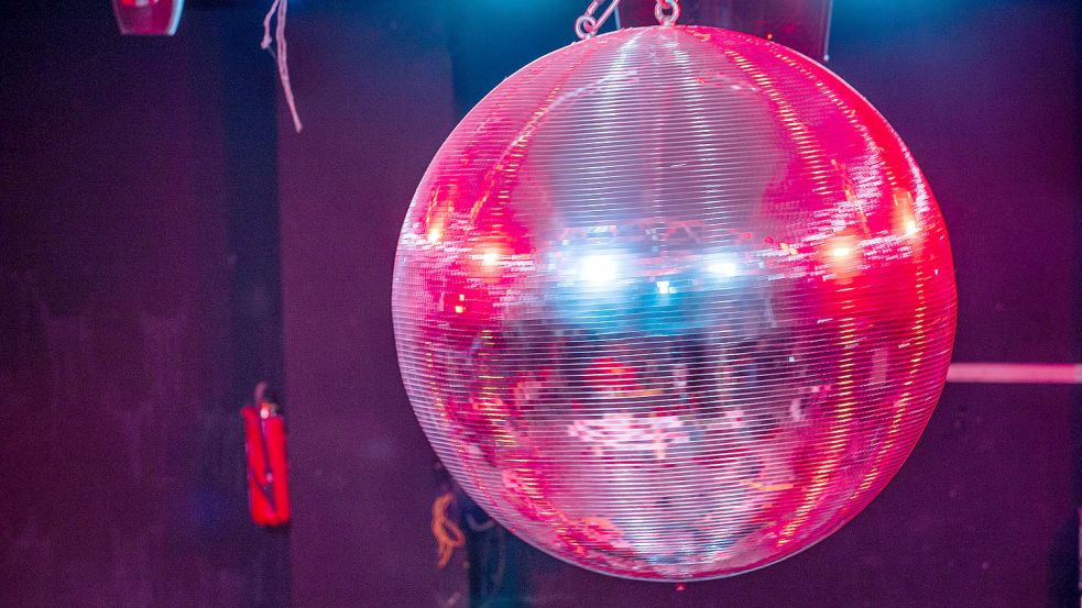 Die farbig beleuchtete Discokugel dreht sich über der Tanzfläche in einer geschlossenen Diskothek. Foto: DPA