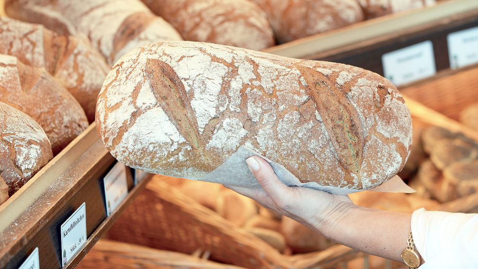 Eine Verkäuferin hält einen Laib Brot in der Hand. Foto: DPA